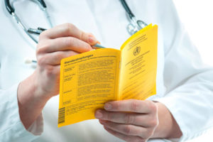 A doctor writing in a small yellow booklet