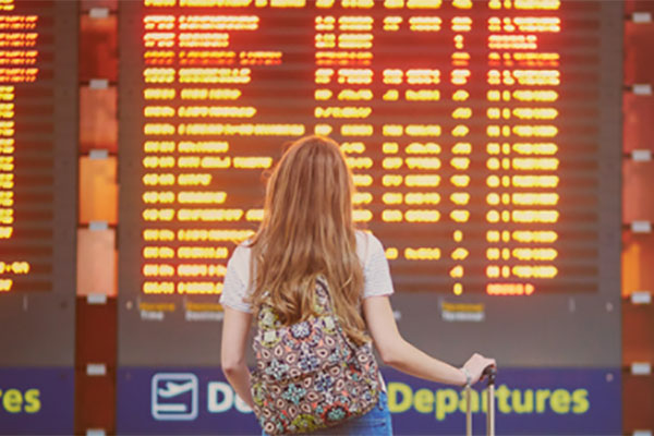 A young woman traveller is looking up at the departure board in an airport