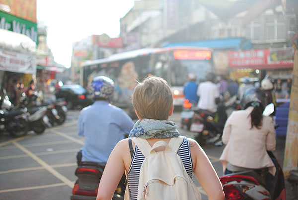 A woman traveller is stood on a busy road